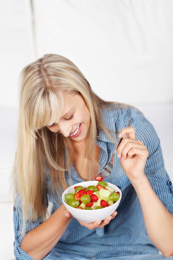 Glückliche Frau, die frischen Obstsalat isst lizenzfreies stockfoto Glückliche Frau, die frischen Obstsalat isst lizenzfreies stockfoto