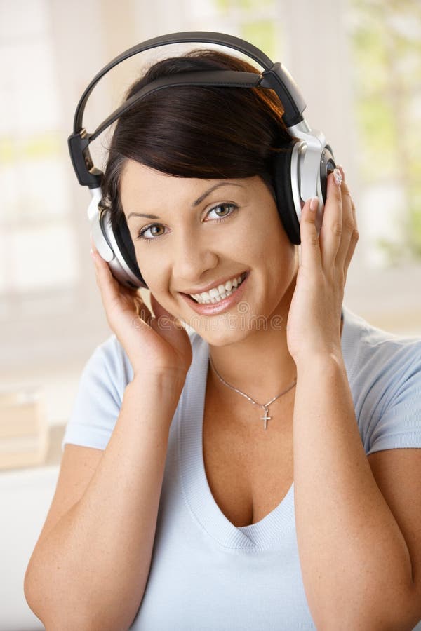 Happy young woman enjoying music on headphones, smiling. Happy young woman enjoying music on headphones, smiling.