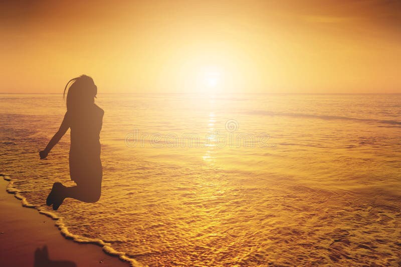 Glückliche Frau, die in Seestrand Sonnenuntergangschattenbild springt