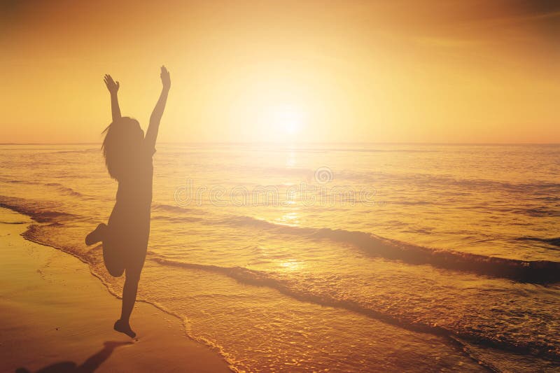 Glückliche Frau, die in Seestrand Sonnenuntergangschattenbild springt