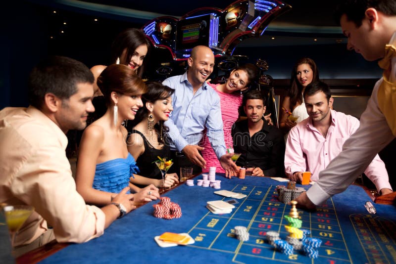 Glückliche Freunde, die Roulette in einem Kasino spielen lizenzfreie stockfotografie Glückliche Freunde, die Roulette in einem Kasino spielen lizenzfreie stockfotografie