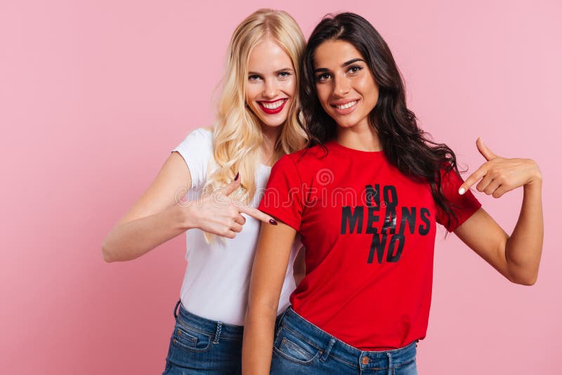Glückliche Freundinnen, die auf Hemd mit der Phrase und Lächeln lokalisiert zeigen lizenzfreie stockfotos Glückliche Freundinnen, die auf Hemd mit der Phrase und Lächeln lokalisiert zeigen lizenzfreie stockfotos