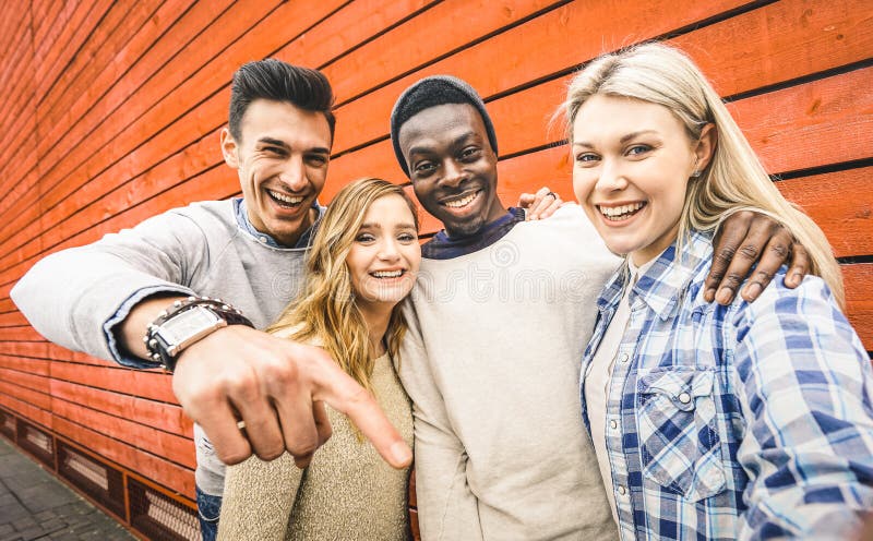 Glückliche Gruppe multirassischer Freunde, die sich mit intelligentem Mobilfunk selber macht stockfoto