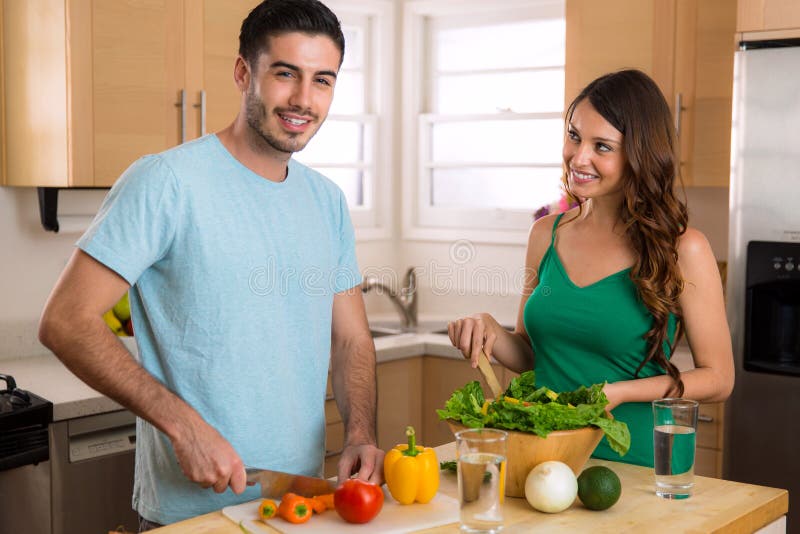 Glückliche gesunde junge Paare des strengen Vegetariers, die zu Hause Gemüse kochen lizenzfreies stockbild Glückliche gesunde junge Paare des strengen Vegetariers, die zu Hause Gemüse kochen lizenzfreies stockbild