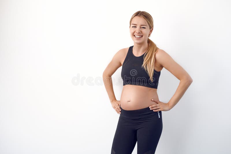Glückliche gesunde junge schwangere Frau in der schwarzen Sportkleidung lizenzfreie stockfotos Glückliche gesunde junge schwangere Frau in der schwarzen Sportkleidung lizenzfreie stockfotos