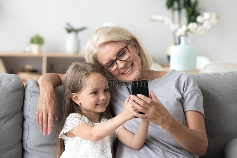 Glückliche Großmutter und nette Enkelin, welche die Mobiltelefonherstellung verwendet lizenzfreie stockfotografie Glückliche Großmutter und nette Enkelin, welche die Mobiltelefonherstellung verwendet lizenzfreie stockfotografie