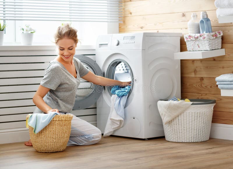 Glückliche Hausfraufrau in der Waschküche mit Waschmaschine stockbilder