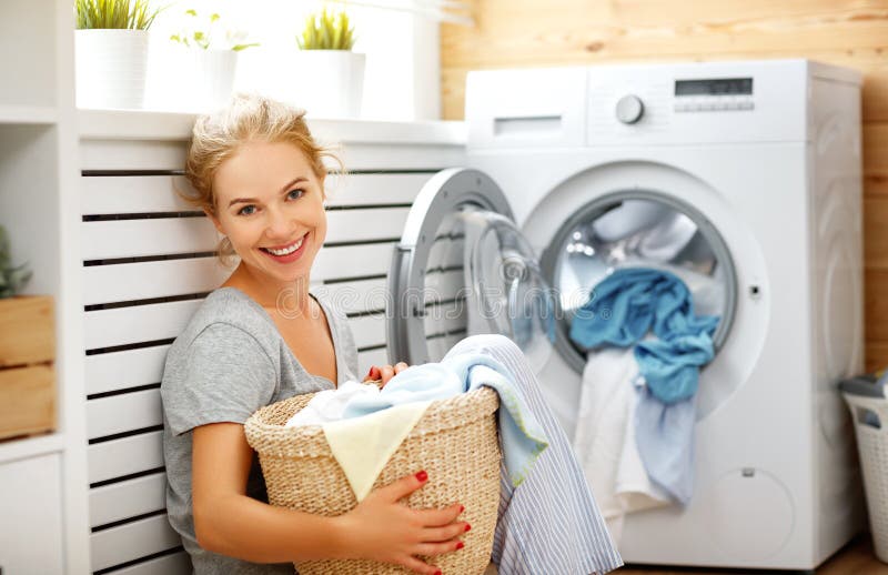 Glückliche Hausfraufrau in der Waschküche mit Waschmaschine lizenzfreie stockfotografie