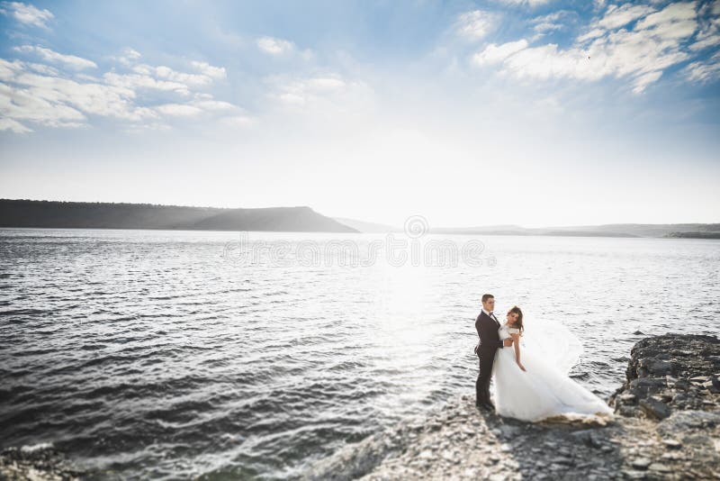 Glückliche Hochzeitspaare, die über schöner Landschaft bleiben stockbild Glückliche Hochzeitspaare, die über schöner Landschaft bleiben stockbild