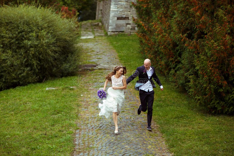 Glückliche Hochzeitspaarläufe im Park stockfotos Glückliche Hochzeitspaarläufe im Park stockfotos