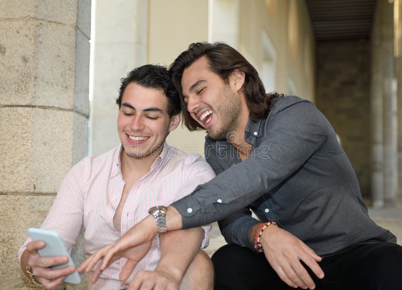 Glückliche homosexuelle Paare, die mit ihrem Handy lächeln stockfotografie