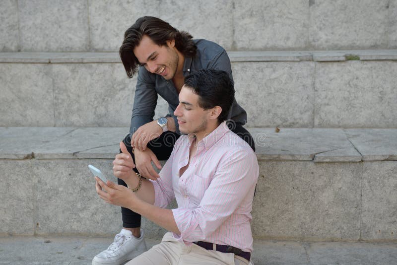 Glückliche homosexuelle Paare mit ihrem Handy lizenzfreie stockfotografie