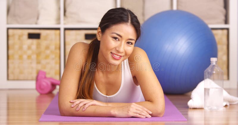 Glückliche japanische Frau, die auf dem Yoga matt liegt stockfotografie Glückliche japanische Frau, die auf dem Yoga matt liegt stockfotografie