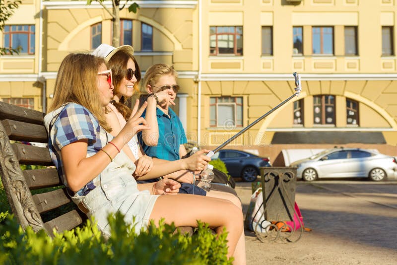 Gl?ckliche 4 Jugendfreunde oder hohe Sch?ler haben Spa? und sprechen und lesen das Telefon und machen selfie Foto in der Stadt au lizenzfreie stockbilder Gl?ckliche 4 Jugendfreunde oder hohe Sch?ler haben Spa? und sprechen und lesen das Telefon und machen selfie Foto in der Stadt au lizenzfreie stockbilder