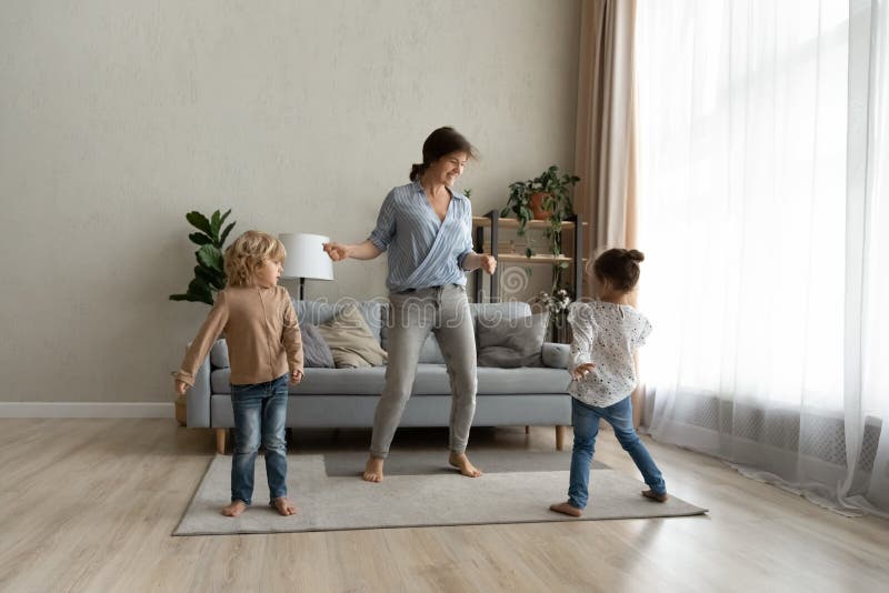 Glückliche junge alleinerziehende Mutter tanzt mit süßen Kindern. stockfoto