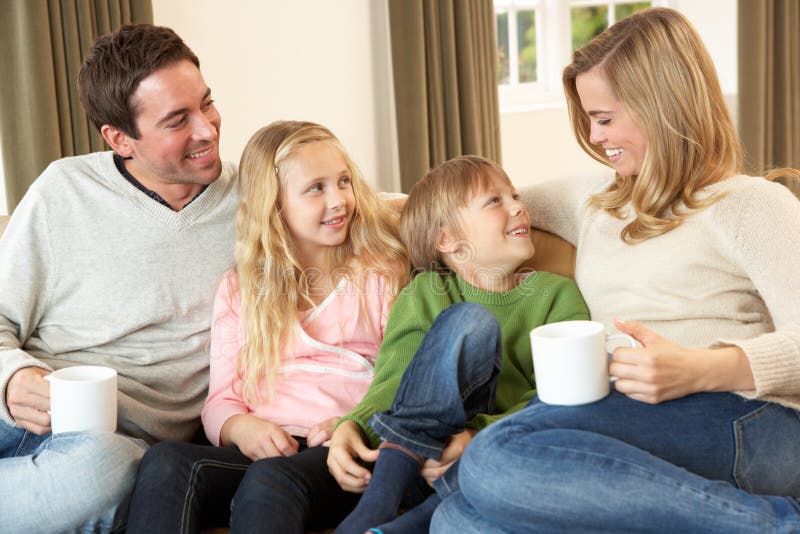 Glückliche junge Familie, die auf Sofa sitzt und spricht stockfotografie Glückliche junge Familie, die auf Sofa sitzt und spricht stockfotografie