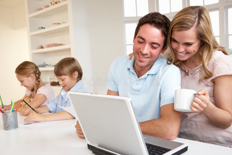 Glückliche junge Familie, die einen Laptop schaut und liest
