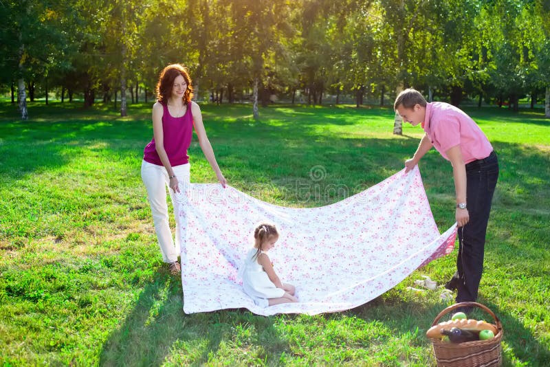 Glückliche junge Familie, die Picknick an der Wiese hat lizenzfreie stockbilder Glückliche junge Familie, die Picknick an der Wiese hat lizenzfreie stockbilder