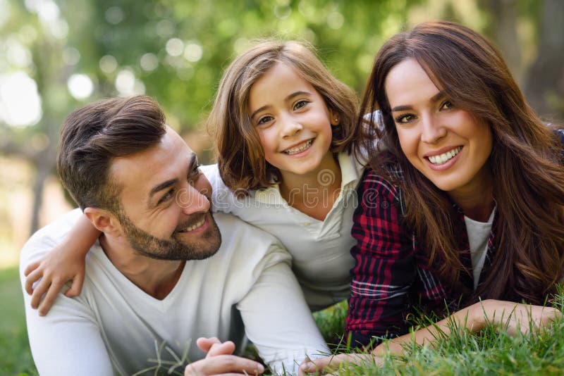 Glückliche junge Familie in einem städtischen Park lizenzfreies stockbild Glückliche junge Familie in einem städtischen Park lizenzfreies stockbild