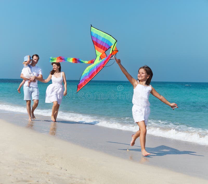 Glückliche junge Familie mit dem Fliegen eines Drachens lizenzfreies stockbild Glückliche junge Familie mit dem Fliegen eines Drachens lizenzfreies stockbild