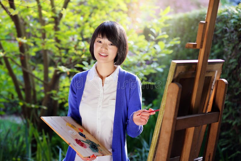 Happy young woman painting a canvas in the garden . Creativity and relax. Happy young woman painting a canvas in the garden . Creativity and relax