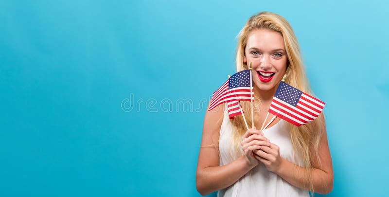 Glückliche junge Frau, die eine amerikanische Flagge anhält