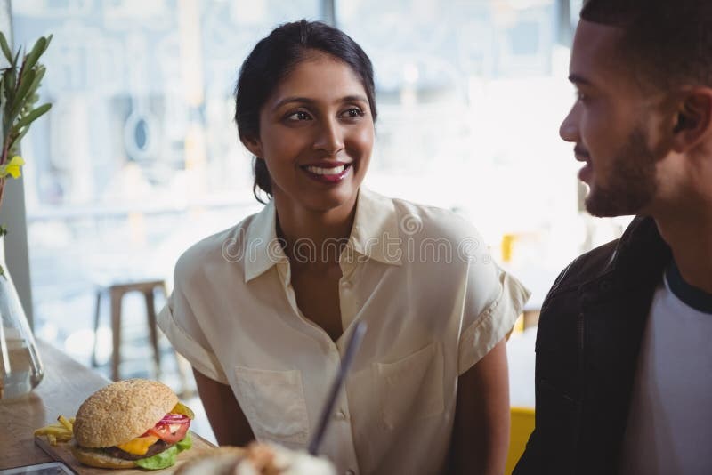 Glückliche junge Frau, die Mann im Café betrachtet lizenzfreies stockbild Glückliche junge Frau, die Mann im Café betrachtet lizenzfreies stockbild