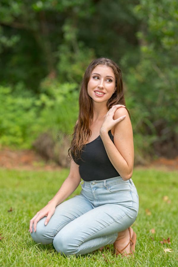 Glückliche junge Frau in einer besetzenden Pose lächelnde Naturszene stockbild Glückliche junge Frau in einer besetzenden Pose lächelnde Naturszene stockbild