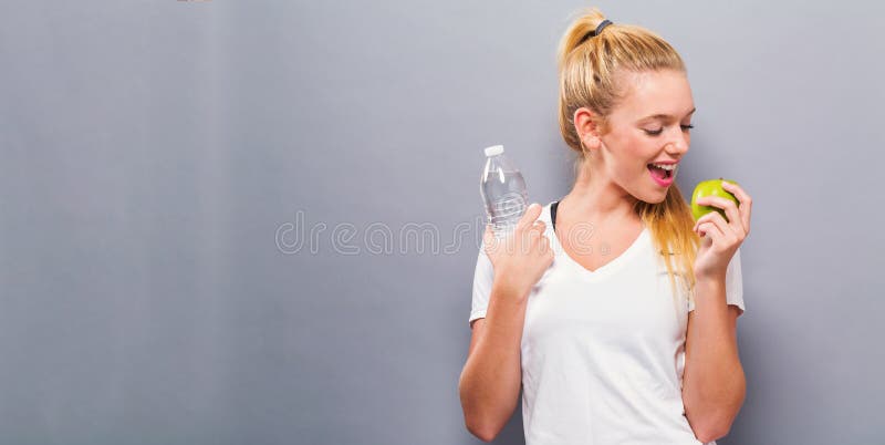 Glückliche junge Frau mit einem Apfel und einer Wasserflasche
