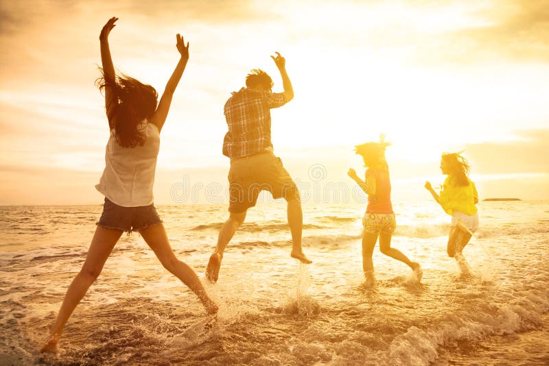 Glückliche junge Leute, die auf den Strand tanzen lizenzfreies stockbild