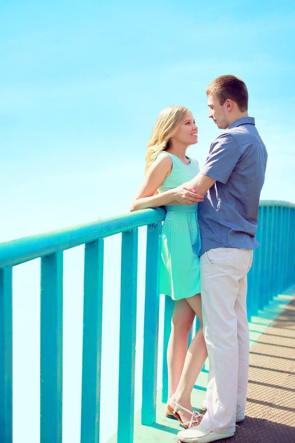 Glückliche junge Paare in der Liebe auf der Brücke über blauem Himmel an der Stadt parken - Valentinsgrußtages-Verhältnis-Konzept lizenzfreie stockbilder Glückliche junge Paare in der Liebe auf der Brücke über blauem Himmel an der Stadt parken - Valentinsgrußtages-Verhältnis-Konzept lizenzfreie stockbilder