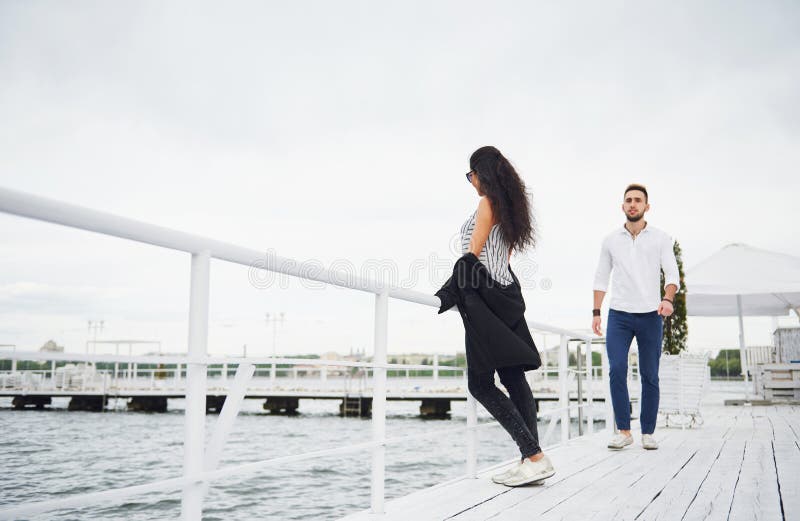 Glückliche junge Paare in der Liebe in einem schönen Kleid, werfend auf dem Pier nahe dem Wasser auf stockbilder Glückliche junge Paare in der Liebe in einem schönen Kleid, werfend auf dem Pier nahe dem Wasser auf stockbilder