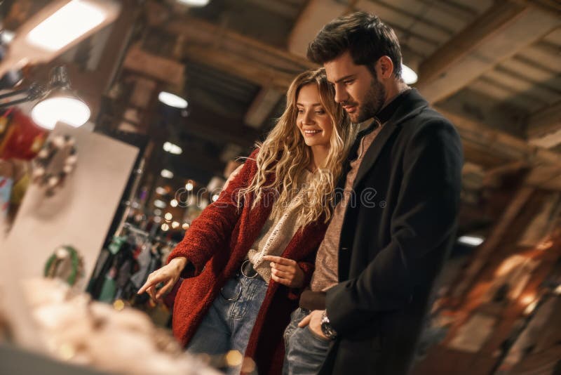 Glückliche junge Paare, die handgemachten nachgemachten Schmuck am kleinen Straßenmarkt wählen stockfotografie Glückliche junge Paare, die handgemachten nachgemachten Schmuck am kleinen Straßenmarkt wählen stockfotografie