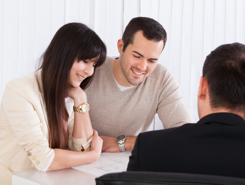 Glückliche junge Paare, die mit Berater sich besprechen stockfoto Glückliche junge Paare, die mit Berater sich besprechen stockfoto