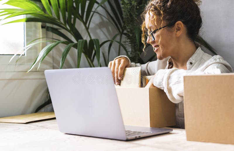 Glückliche junge Unternehmerin, die das Paket und die Lieferung für den Express Kurierdienst vorbereitet, nachdem sie Artikel onli stockfotos