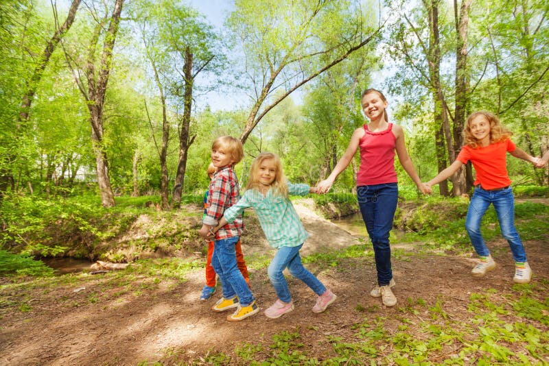 Glückliche Kinder, die in das Parkhändchenhalten gehen stockfotos Glückliche Kinder, die in das Parkhändchenhalten gehen stockfotos