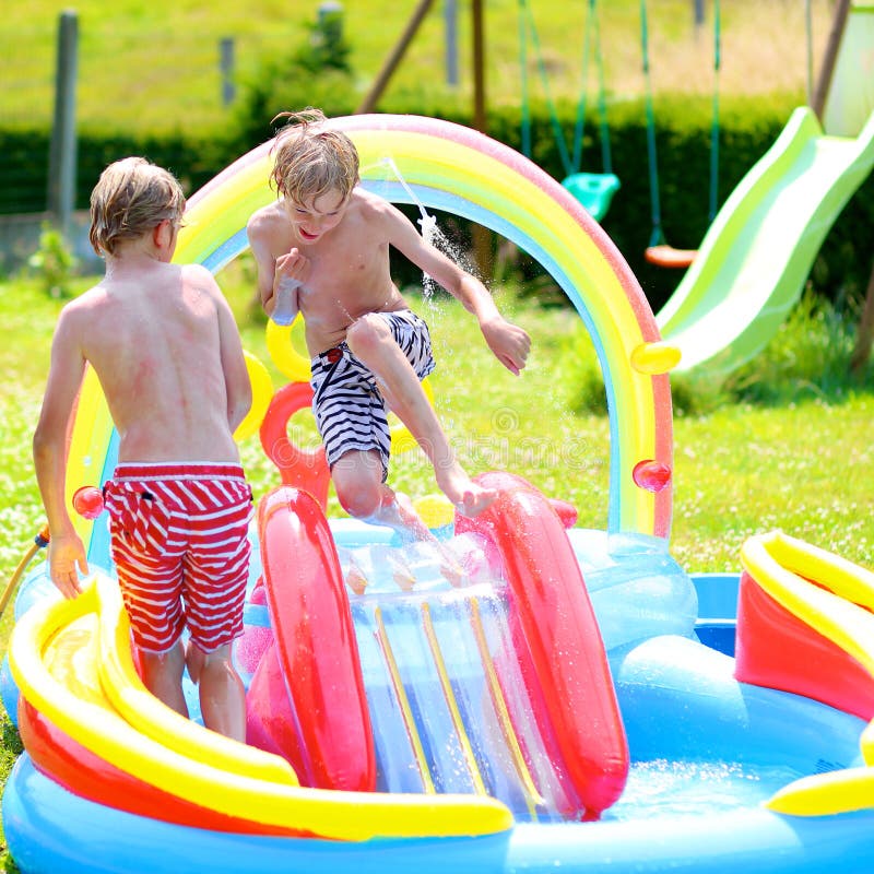 Glückliche Kinder, die im aufblasbaren Gartenpool spritzen stockfoto Glückliche Kinder, die im aufblasbaren Gartenpool spritzen stockfoto