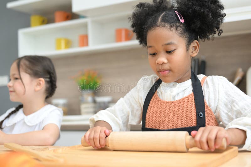 Glückliche Kinder, die mit Mehl spielen und in der Küche lachen stockfotos