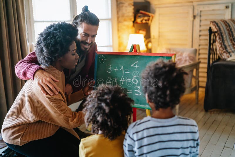 Glückliche Kinder lernen Mathematik mit multiethnischen Eltern zu Hause. Konzept für das Glück der Familie lizenzfreie stockfotografie
