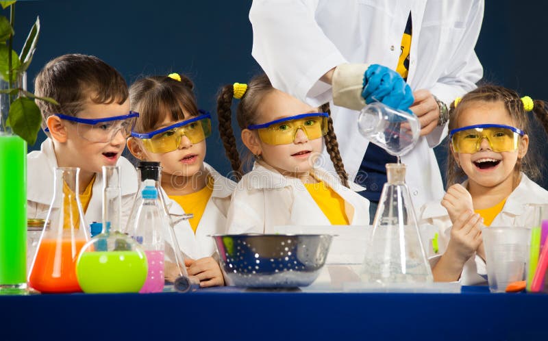 Glückliche Kinder mit dem Wissenschaftler, der Wissenschaft tut, experimentiert im Labor