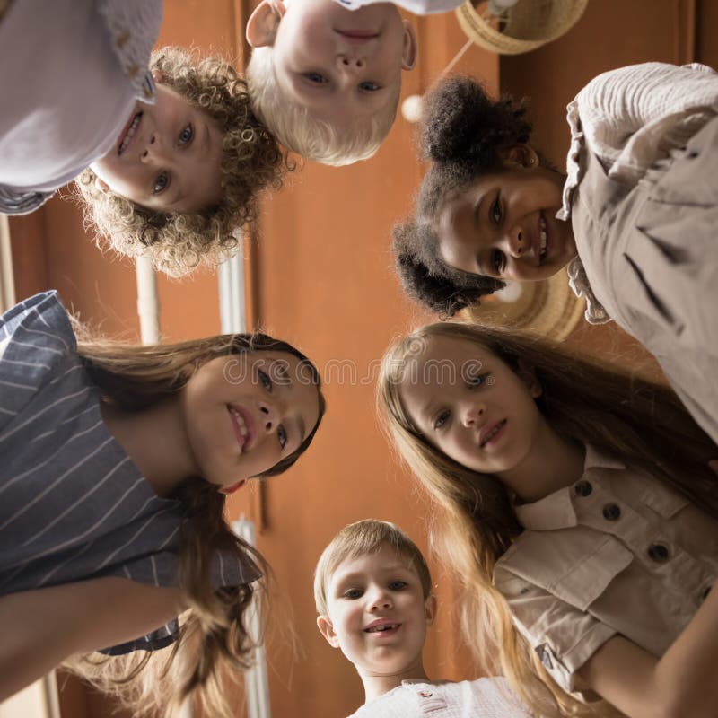 Glückliche kleine Kinder, die im Kreis stehen und lächeln, sehen Kamera stockfotografie