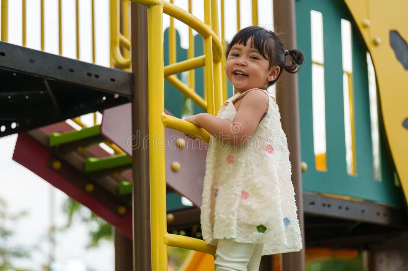 Glückliche Kleinkind, die auf dem Spielplatz im Park spielen und klettern stockbilder