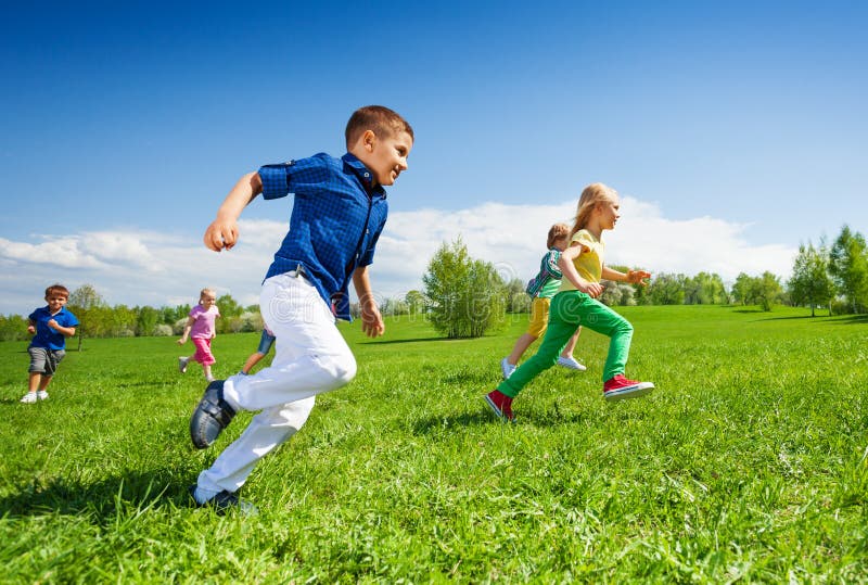 Glückliche laufende Kinder im grünen Park während des Tages stockbild Glückliche laufende Kinder im grünen Park während des Tages stockbild