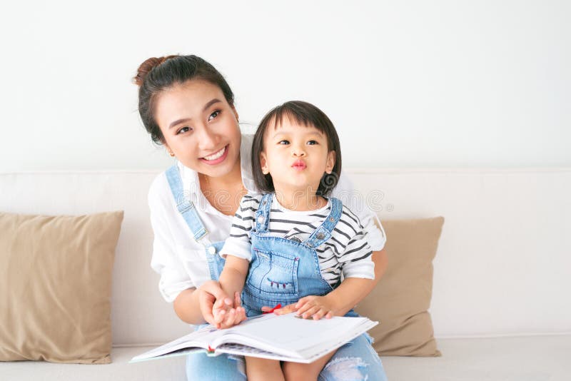 Glückliche liebevolle Familie Recht junge asiatische Mutter, die ein Buch zu liest lizenzfreies stockfoto