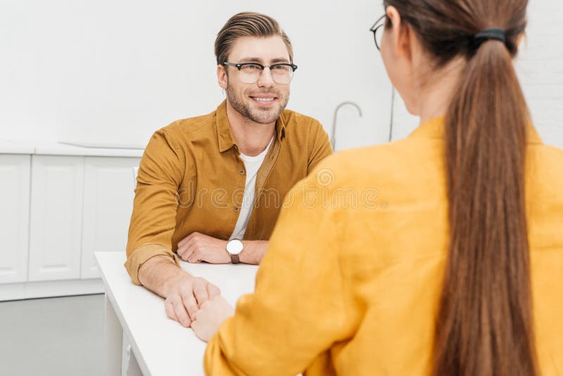 Glückliche liebevolle Paare, die zusammen auf Küche sitzen lizenzfreies stockbild