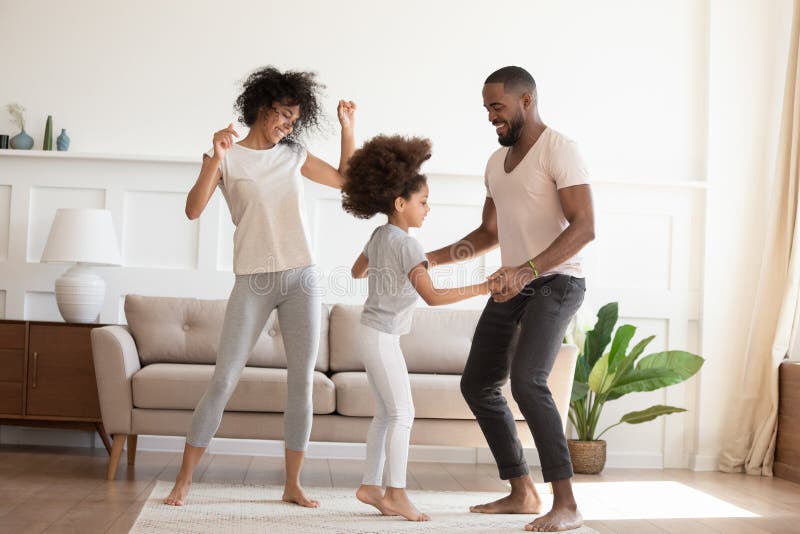 Glückliche lustige aktive afrikanische Familie mit der Tochter, die zu Hause tanzt
