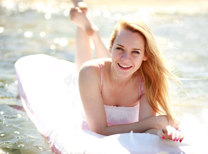 Glückliche lächelnde Frau liegt auf einem Wasserbett am Sommertag lizenzfreies stockbild Glückliche lächelnde Frau liegt auf einem Wasserbett am Sommertag lizenzfreies stockbild