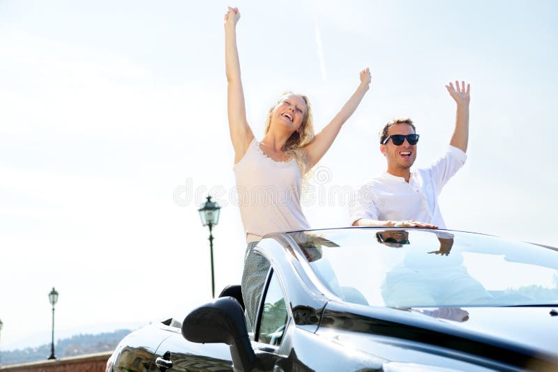 Happy people in car driving on road trip. Young couple having fun dancing and cheering in car driving on travel vacation together. Lifestyle with beautiful cheerful lovers, young women and man. Happy people in car driving on road trip. Young couple having fun dancing and cheering in car driving on travel vacation together. Lifestyle with beautiful cheerful lovers, young women and man.