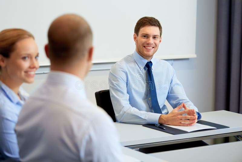 Glückliche Mitarbeiter, die im Büro sich treffen und sprechen lizenzfreies stockbild Glückliche Mitarbeiter, die im Büro sich treffen und sprechen lizenzfreies stockbild