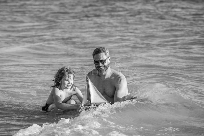 Glückliche Momente für Vater und Sohn. Pater-Sohn Beach Abenteuer Spielen mit Spielzeug Schiff. Beziehung zwischen Vater und Sohn. stockbild
